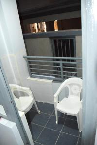 einen Balkon mit zwei weißen Stühlen und einem Waschbecken in der Unterkunft One Bedroom BnB in Thika Town7 in Thika