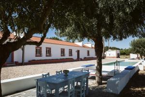 a table under a tree next to a swimming pool at Nature Forest - Herdade de Martingil in Chouto