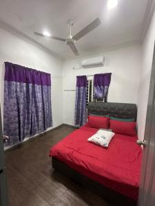 1 dormitorio con cama roja y cortinas moradas en DHIA HOMESTAY en Machang