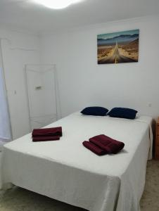 ein Schlafzimmer mit einem weißen Bett mit roten Handtüchern darauf in der Unterkunft Casa Duque in Prado del Rey