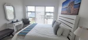 a bedroom with a white bed and a window at 19 Tontiki in Ballito +18 photos
