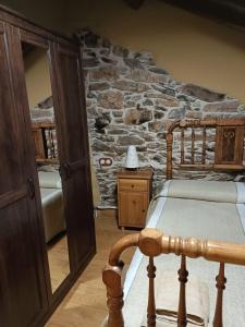 a bedroom with a stone wall with a bed and a table at Casa do Eiró in Lago de Carucedo