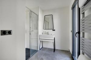 Baño blanco con lavabo y espejo en Drawing House, en París