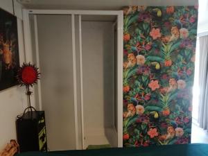 a bedroom with a tropical wallpaper on the wall at Tiny house cosy in Anduze