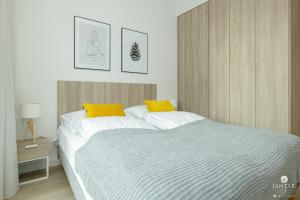 a bedroom with a large bed with yellow pillows at Shellter Apartments Villas - by Jantar Apartamenty in Rogowo