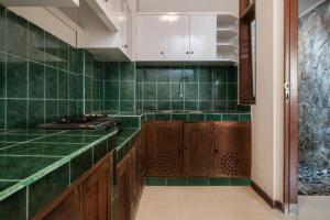 una cocina con paredes de azulejos verdes y armarios de madera. en Villa Bunga Hotel, en Seminyak