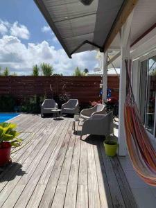 una terraza con sillas y una hamaca en una casa en Villa cosy toute équipée avec piscine, en Le Gosier