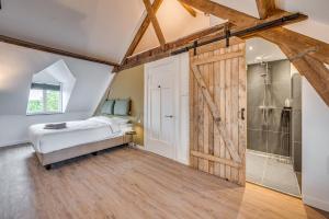 a bedroom with a bed and a sliding barn door at La Dominotte Arcen in Arcen