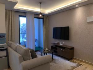 a living room with a couch and a flat screen tv at 1-BR Gem Near GTC, Westlands 5G in Nairobi