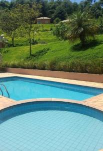 una gran piscina azul con vistas a un campo en Recanto dos Beija Flores, Chalé lantana e en Monte Alegre do Sul