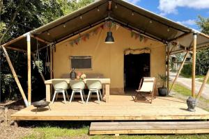 une tente avec une table et des chaises sur une terrasse en bois dans l'établissement Glamping-tent 'Yatra Nirvana' met privé keuken en regendouche, à Grou