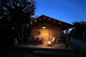 a woman sitting at a table in a tent at night at Glamping-tent 'Yatra Nirvana' met privé keuken en regendouche in Grou