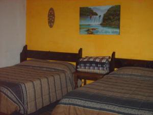 Habitación con 2 camas y una cascada en la pared. en Hotel Villa Santo Domingo, en Concepción de Ataco