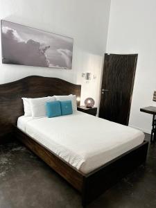 ein Bett mit zwei blauen Kissen in einem Schlafzimmer in der Unterkunft Cloud 11 Jamaica in Treasure Beach