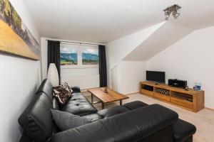 a living room with a black leather couch and a table at Ferienwohnung Kupfer in Sonthofen