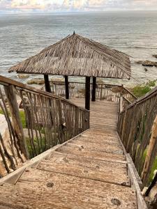 un paseo marítimo de madera que conduce al océano con una cabaña en Cloud 11 Jamaica en Treasure Beach