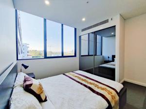 1 dormitorio con 2 camas y 2 ventanas grandes en Sun-filled Apt w Stunning Open Views of Park&City, en Sídney