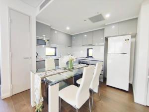 a kitchen with a dining table and white chairs at Sun-filled Apt w Stunning Open Views of Park&City in Sydney