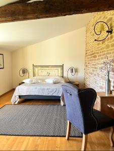 een slaapkamer met een bed en een stoel bij La côte des Blancs - Domaine viticole & maison d'hôtes in Vinzelles