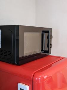 Un four micro-ondes est installé au-dessus d'un réfrigérateur rouge. dans l'établissement marugame stop - Vacation STAY 50031v, à Marugame