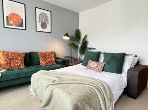 uma sala de estar com uma cama e um sofá verde em Bright 1 bed central Worthing with sofa bed sleeps up to 4 close to beach by Eagle Owl Property em Worthing