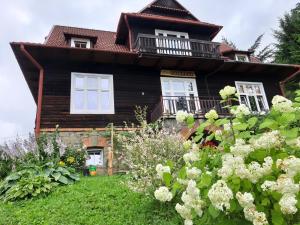 a large wooden house with white windows and flowers at Willa Marylka in Piwniczna-Zdrój