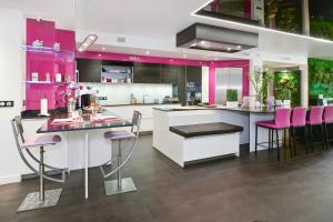 a kitchen with pink cabinets and pink chairs at Le Loft Oasis Prestige - Piscine et jacuzzi in Pringy