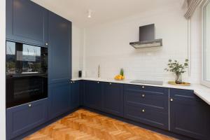 kuchnia z niebieskimi szafkami, białymi ścianami i drewnianymi podłogami w obiekcie Apartment in the Centre of Warsaw by Renters w Warszawie
