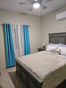 a bedroom with a large bed with blue curtains at SG Apartment Complex (Apt #1) in Linstead