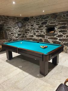 a pool table in front of a stone wall at Casa do avô tamanqueiro in Arco de Baúlhe