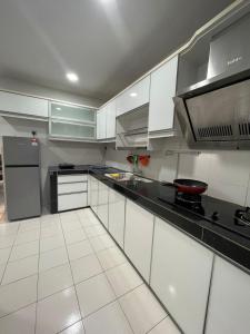 a kitchen with white cabinets and a black counter top at FREE Wi-fi 100mbps I Emerald Cove Rawang in Rawang