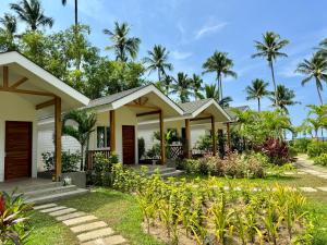 a house on the beach with palm trees in the background at Nacpan Beach Villas in El Nido