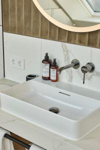 DAS LORNSEN - Serviced Luxury Apartments في فيسترلاند: بالوعة بيضاء في الحمام مع مرآة