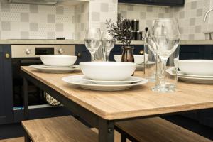 a wooden table with bowls and wine glasses on it at Peaceful home Nr Roundhay Park in Moortown