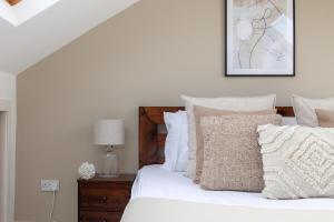 1 dormitorio con 1 cama con sábanas y almohadas blancas en The Westbourne Park Collection en Londres