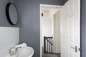 een badkamer met een witte wastafel en een spiegel bij The Crescent in Witton Gilbert