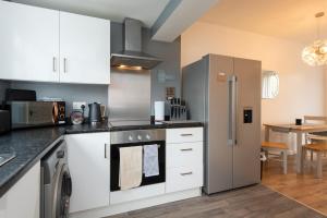 a kitchen with white cabinets and a stainless steel refrigerator at The Crescent in Witton Gilbert