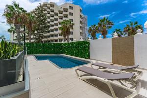 a swimming pool with two lounge chairs and a television at BAL Apartments Adults Only in Arona