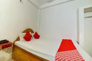 Habitación pequeña con cama con almohadas rojas en OYO Flagship Mamta Hotel en Hājīpur