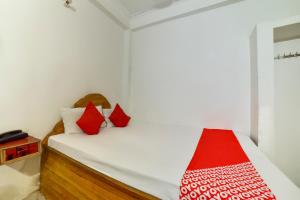 a small bedroom with a bed with red pillows at OYO Flagship Mamta Hotel in Hājīpur