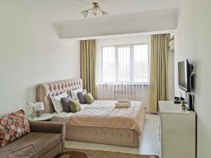 a bedroom with a large bed and a couch at Appartments " Zhetysu-4" in Almaty