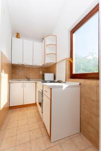 una cocina con armarios blancos y una ventana en Apartments MARIJA, en Okrug Donji