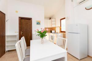 kuchnia z białym stołem i białą lodówką w obiekcie Apartments MARIJA w mieście Okrug Donji