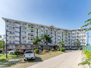 a large apartment building with a car parked in a parking lot at Jolenia by J&J (Near Airport. Netflix. 200Mbps Wi-Fi) in Pusok