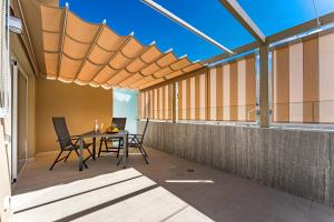 a patio with a table and chairs under a roof at BAL Apartments Adults Only in Arona