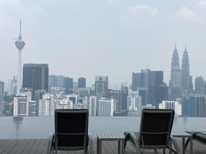 two chairs sitting on a deck with a view of a city at Lalaport Suites At Lucentia Bukit Bintang City Center in Kuala Lumpur