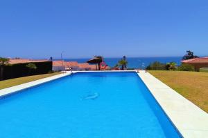 a large blue swimming pool with the ocean in the background at Villa a 150 m de la playa. in Chilches
