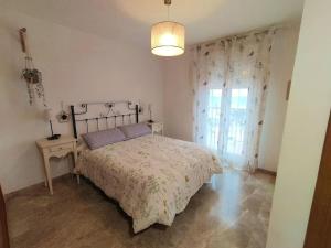 a bedroom with a bed and a lamp and a window at Villa a 150 m de la playa. in Chilches