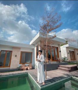a man standing in front of a house next to a swimming pool at Sari Sky Bali in Kubupenlokan