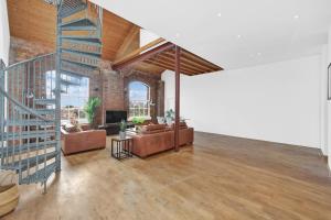 a living room with couches and a staircase in a building at Large Industrial Style 2 Bedroom Flat! in London